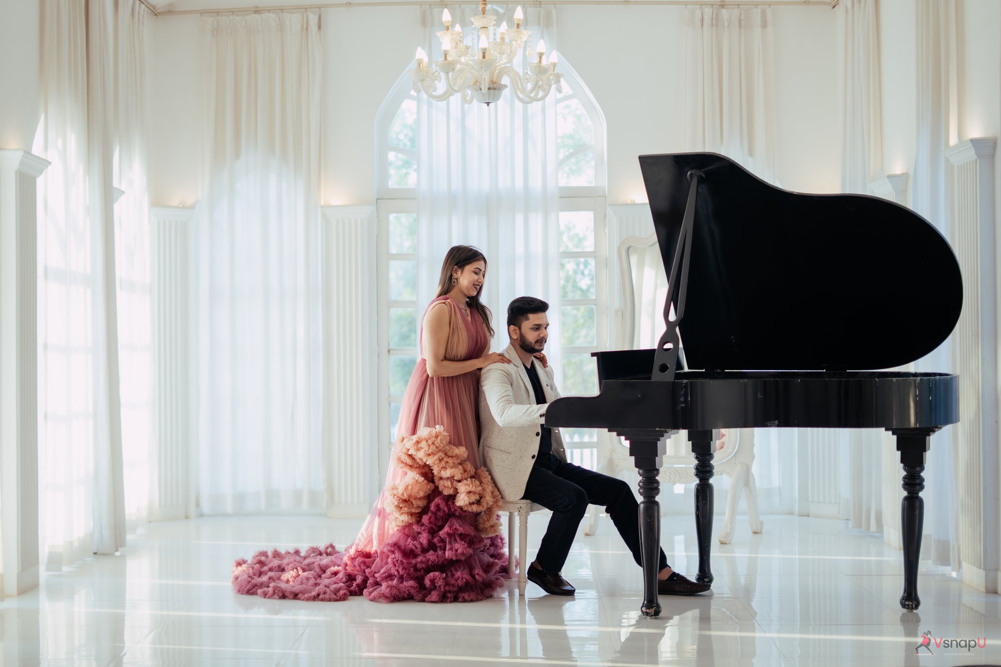 Elegant couple playing a grand piano in a stunning, shining hall during a pre-wedding shoot.